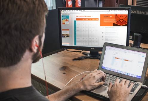 Smart Businessplan: Mensch arbeitet an zwei Bildschirmen